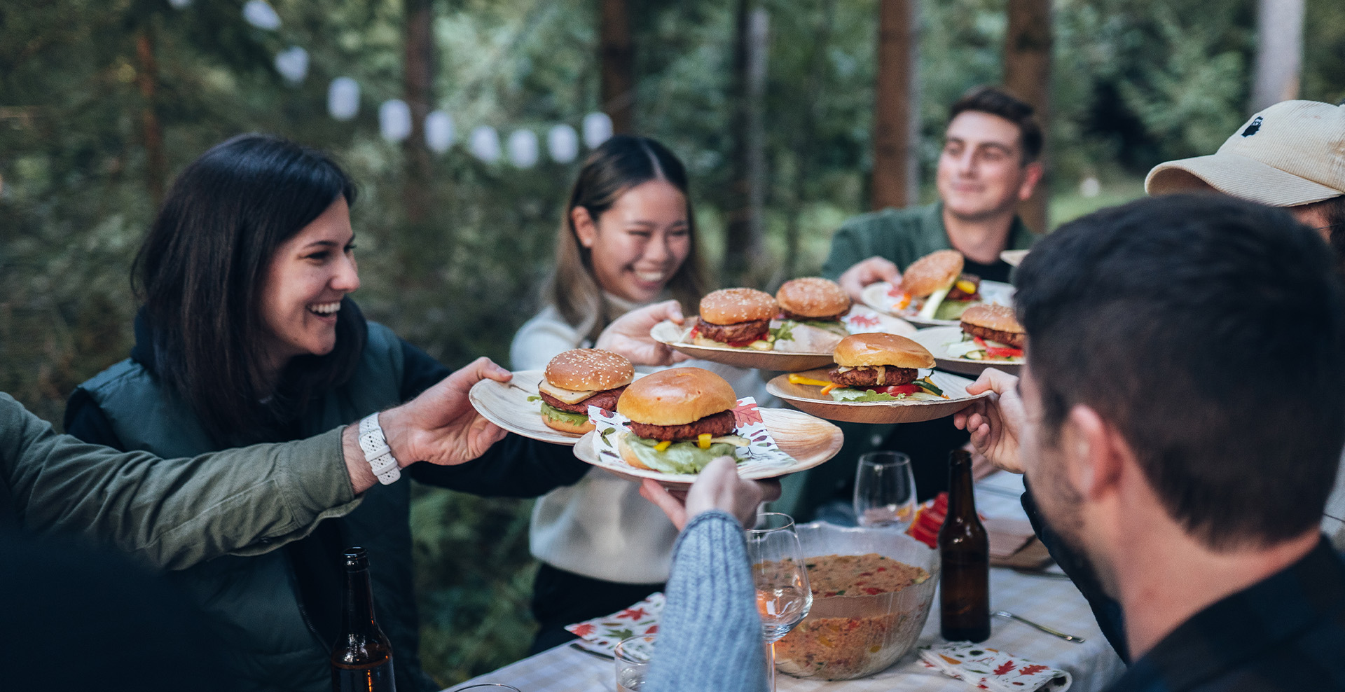 Personen sitzen im Wald und essen einen Burger